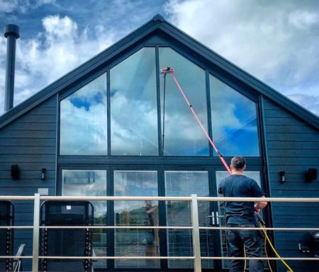 Un homme nettoie une grande fenêtre dans une maison moderne.